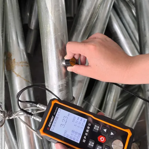 Technician measuring the wall thickness of a galvanized steel light pole with an ultrasonic thickness gauge