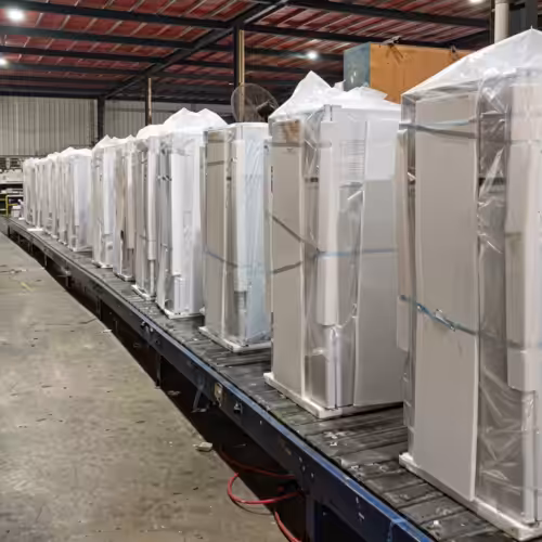 Busy packaging line for Sungreat Energy solar refrigerators with workers boxing units, achieving a daily production capacity of 1000 pieces for global export