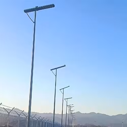 all in one solar street light system installed along rural road with fencing and mountains background