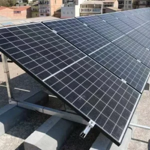 Tilted solar panels installed on flat roof with concrete ballast blocks and metal mounts in an urban setting Title