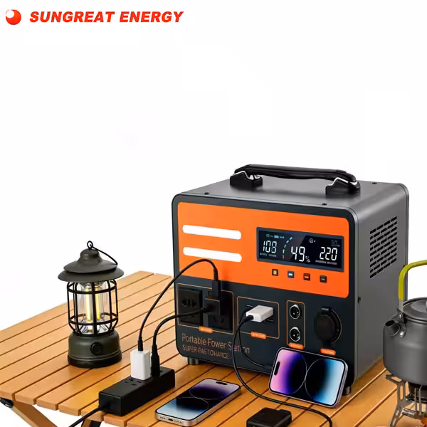 Sungreat Energy portable solar power station with LCD display charging smartphones, camping lights, and appliances on a wooden outdoor table.