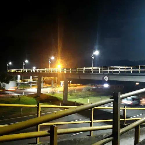Lampioni a LED Sungreat Energy serie LA che illuminano un ponte e un'autostrada di notte, garantendo un'elevata visibilità per il traffico veicolare con distribuzione luminosa di tipo III.