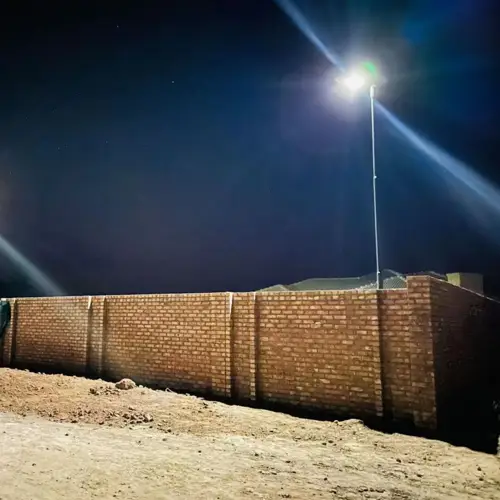 Un lampione a LED della serie LA di Sungreat Energy illumina di notte il muro di cinta di una strada nel deserto del Medio Oriente, dimostrando elevata resistenza e luminosità in ambienti difficili.