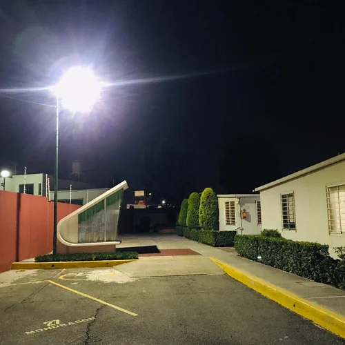 Il lampione a LED Sungreat Energy serie LA illumina di notte l'ingresso e il vialetto di un complesso residenziale, fornendo un'illuminazione di sicurezza ad alta luminosità con distribuzione uniforme.