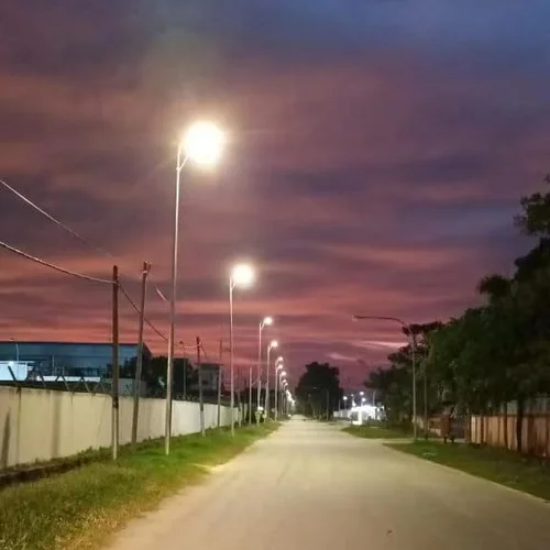 Una fila di lampioni solari integrati della serie QH di Sungreat Energy illumina una strada rurale al crepuscolo, fornendo un'illuminazione affidabile e autonoma per villaggi e sobborghi.