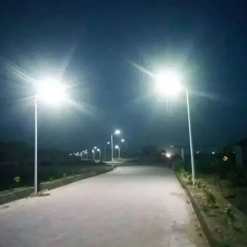Lampioni stradali a energia solare della serie QH di Sungreat Energy che illuminano una strada asfaltata di notte con luminosi fasci LED.