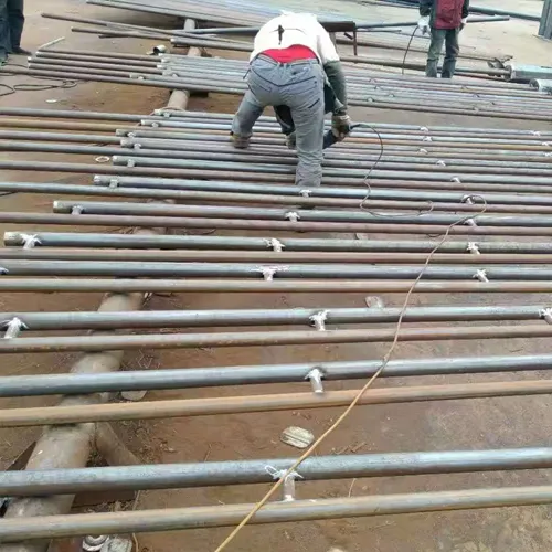 Worker welding and fabricating steel poles for solar street lighting systems at Sungreat Energy manufacturing facility.